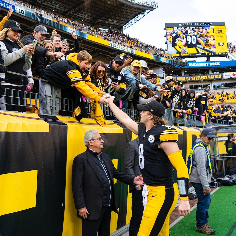 Kenny Pickett hands his gloves to a young fan after the game Sunday at Acrisure Stadium.